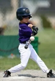 little boy hitting a baseball